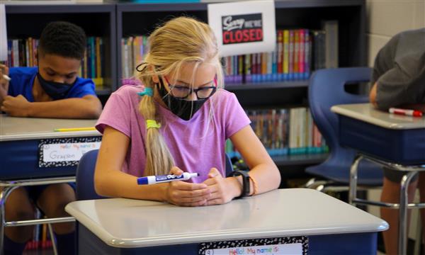 student writes at desk
